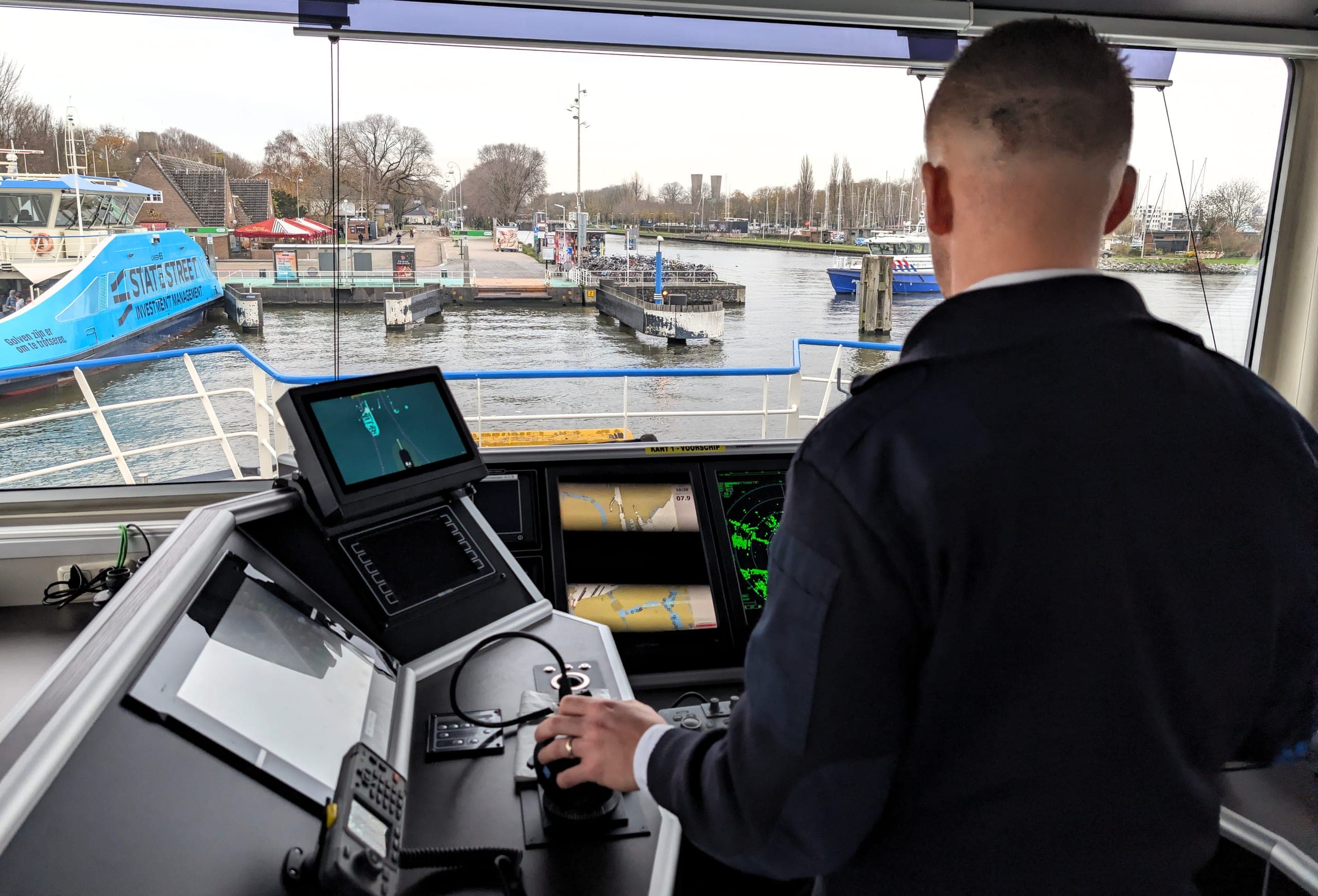 Skipper at the helm with the Roboat docking assistance UI visible on the display