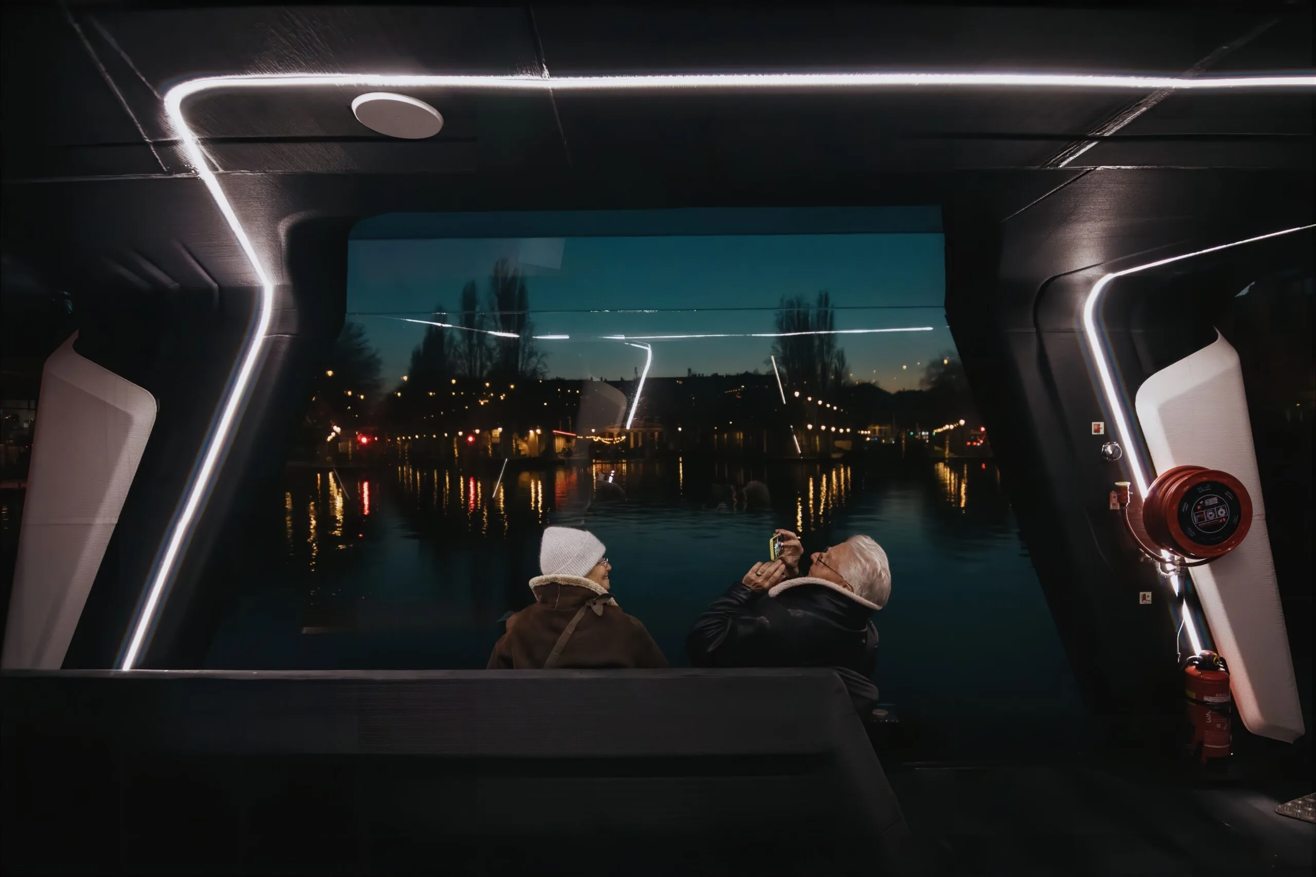 The interior of the Ferry of the Future at night, passengers looking out over the water.